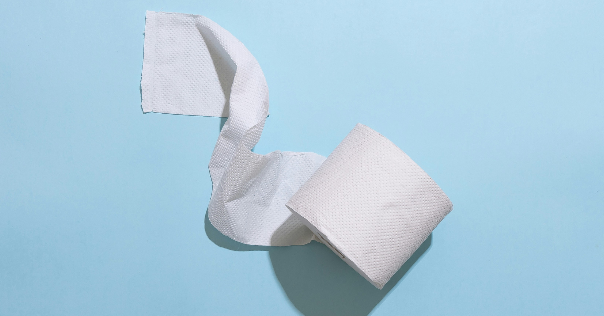 A partial unspooled roll of toilet paper sits against a blue background